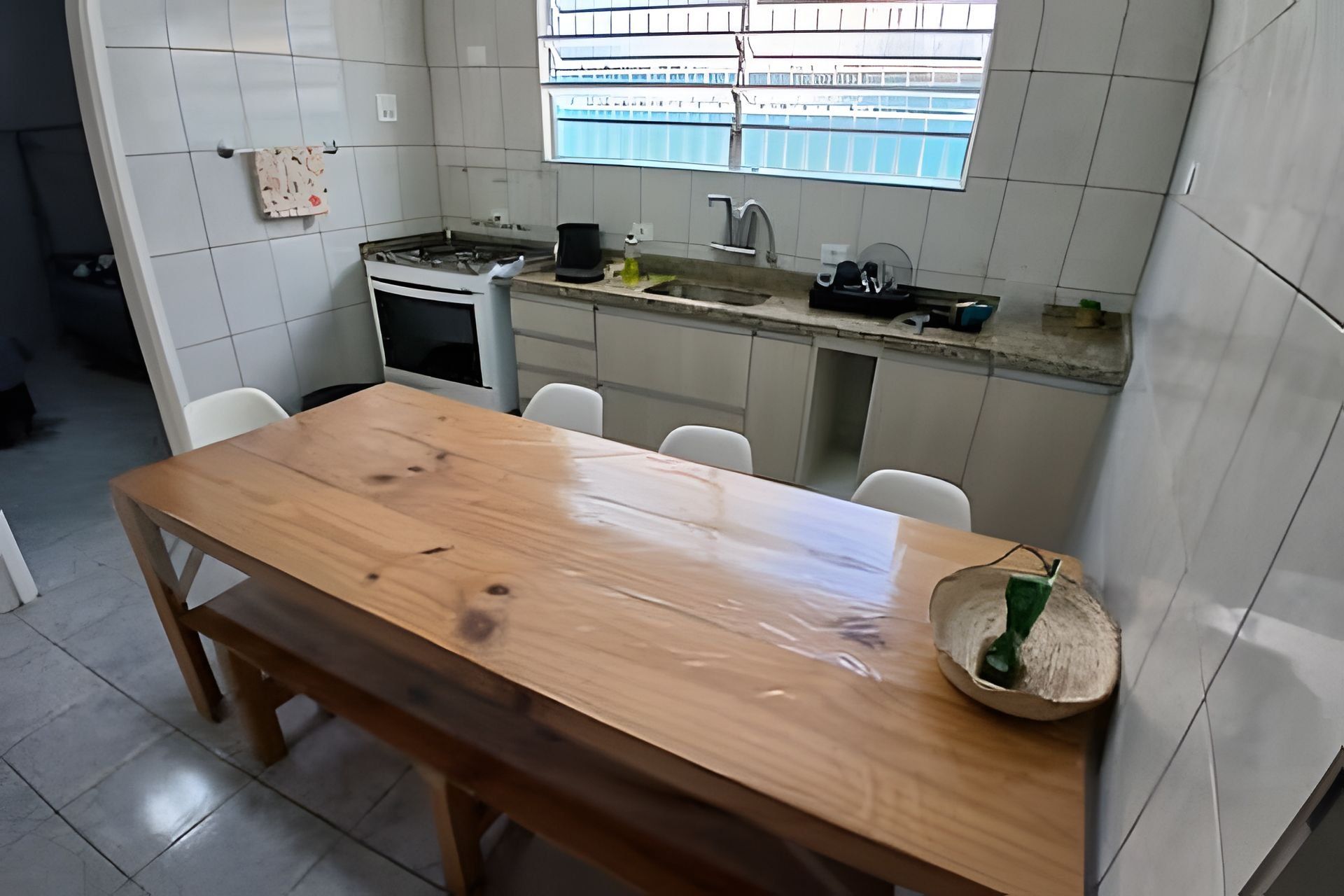 Eine Küche mit Holztisch, weißen Fliesen, einem Fenster und einer Spüle.