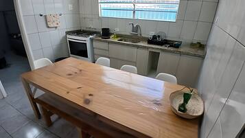 Eine Küche mit Holztisch, weißen Fliesen, einem Fenster und einer Spüle.