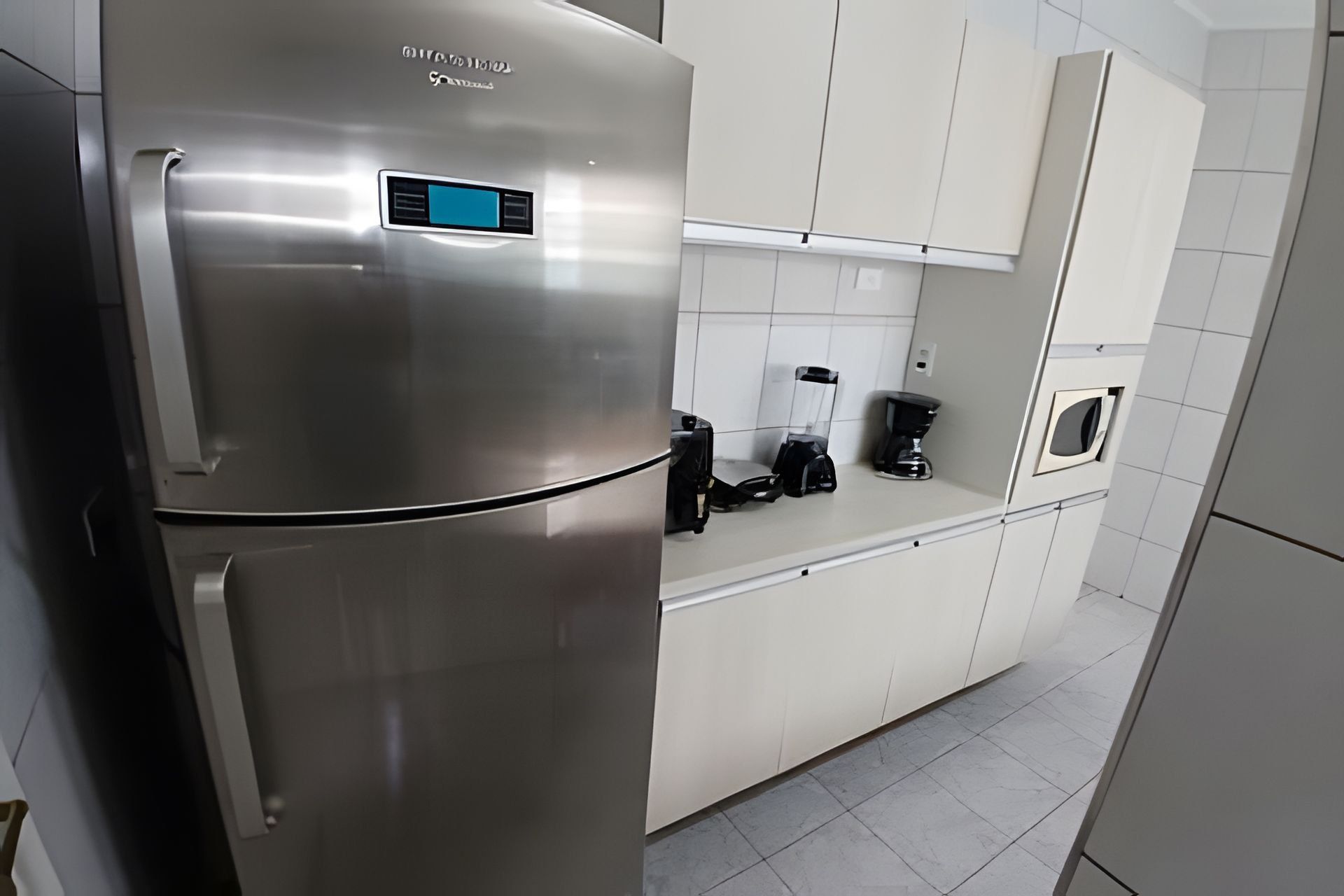 A modern kitchen with a stainless steel refrigerator, a coffee maker, and a microwave.