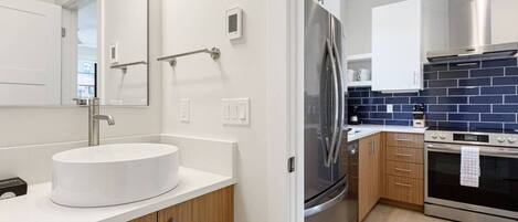 A modern kitchen with a stainless steel refrigerator, a built-in oven, and a white sink.