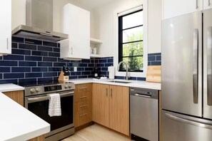 Eine moderne Küche mit Edelstahlgeräten, einem Fenster mit Blick und einer blau gefliesten Spritzschutzwand.