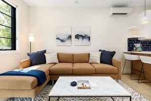Ein modernes Wohnzimmer mit einer Couch, einem Couchtisch und einem Essbereich mit Küchenzeile.