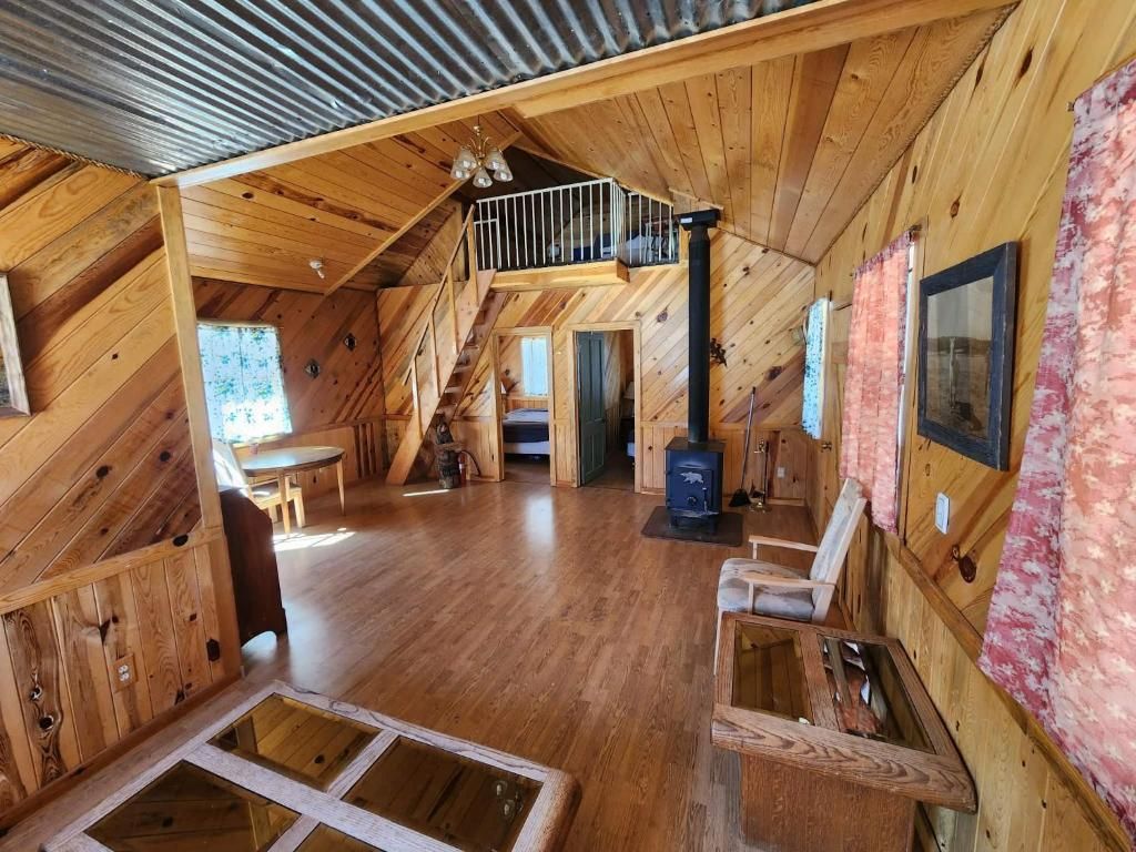 L’intérieur d’une cabane en bois comprend une chambre à coucher située en mezzanine, une cheminée et un coin repas.