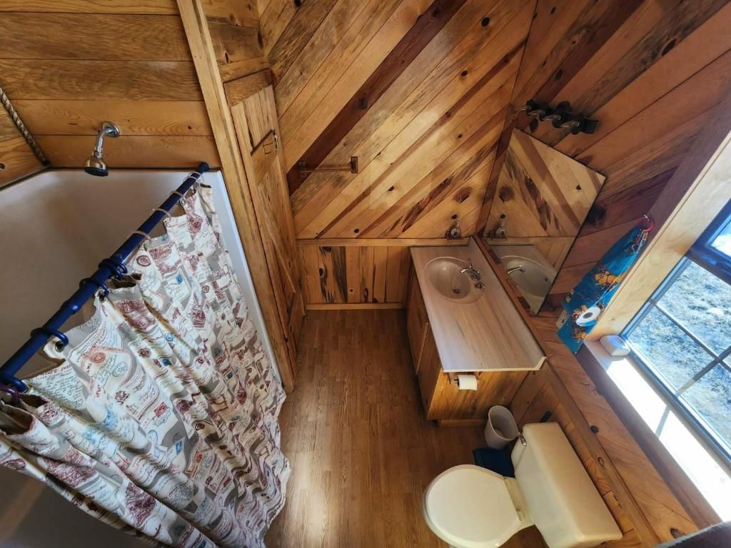 Baño de cabaña de madera con bañera, inodoro y lavamanos.