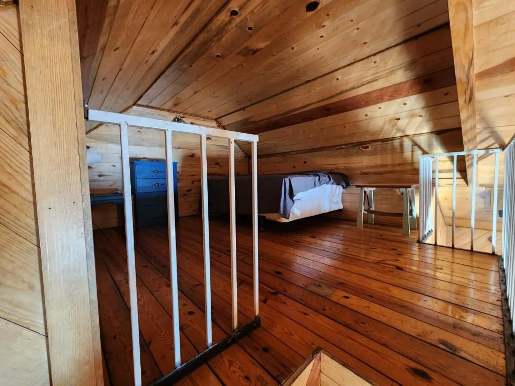Interior de una cabaña de madera con una cama litera, un escritorio pequeño y una ventana.