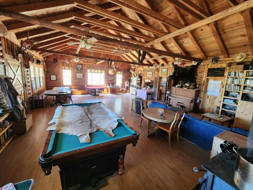 A rustic wooden interior with a pool table, dining area, and various amenities.