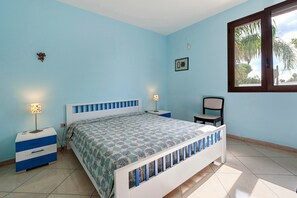 A bedroom with a bed, bedside tables, a chair, and a window.