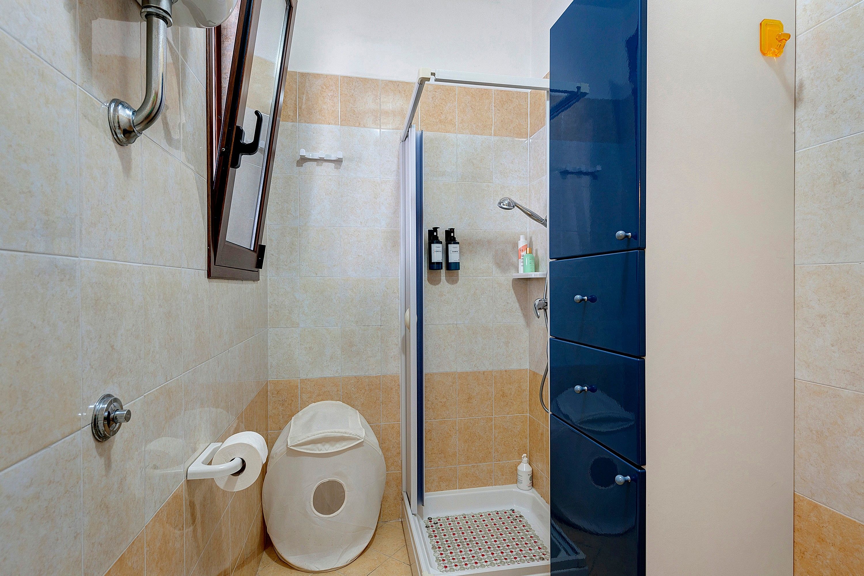 Un baño con ducha, inodoro y armarios para almacenamiento.