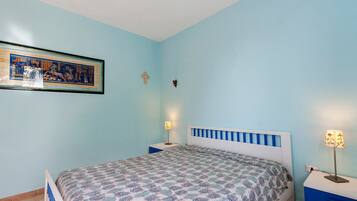 Una camera da letto con un letto, due comodini, una lampada da parete e un quadro incorniciato.