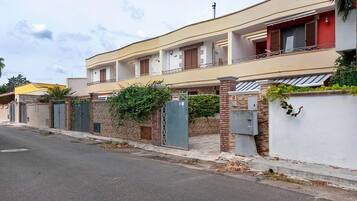 Un immeuble résidentiel à deux étages, doté d’un balcon, d’une entrée sécurisée et d’un mur en briques.