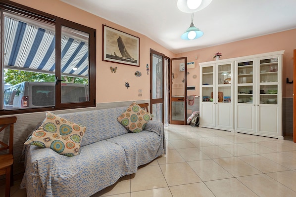 A living room with a sofa, patterned cushions, a framed picture on the wall, and a cabinet with glass doors.