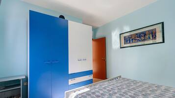 Een slaapkamer met een bed, een kledingkast, een deur en een ingelijste foto aan de muur.