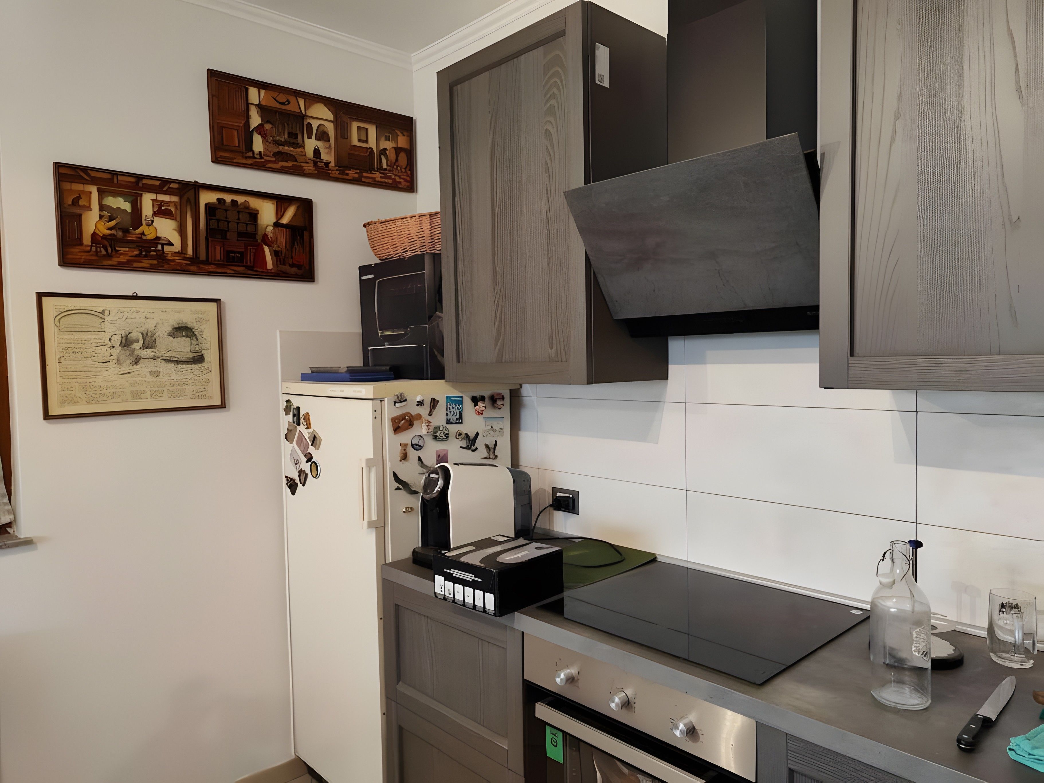 Une cuisine équipée d’un four à micro-ondes encastré, d’un réfrigérateur orné d’aimants, d’une cuisinière et d’un évier.