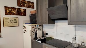 A kitchen with a built-in microwave, a refrigerator with magnets, a stove, and a sink. - Apartment 'Il Melarancio Bb' with Shared Garden, Wi-Fi and Air Conditioning (Monterosi)
