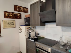 Una cocina equipada con microondas, refrigerador con imanes, estufa y pileta.