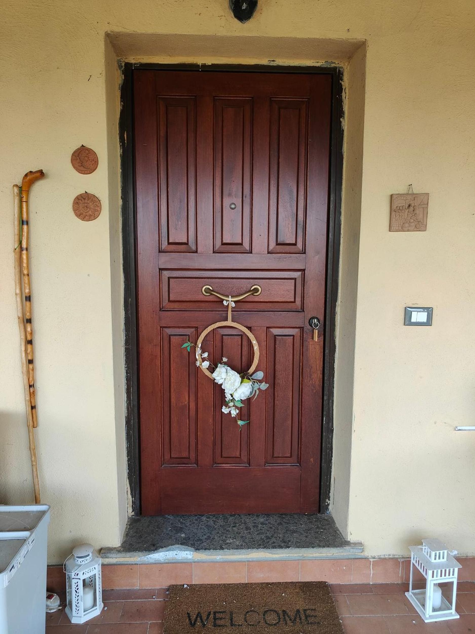 Une porte en bois avec une poignée en laiton, un paillasson et une canne appuyée contre le mur.