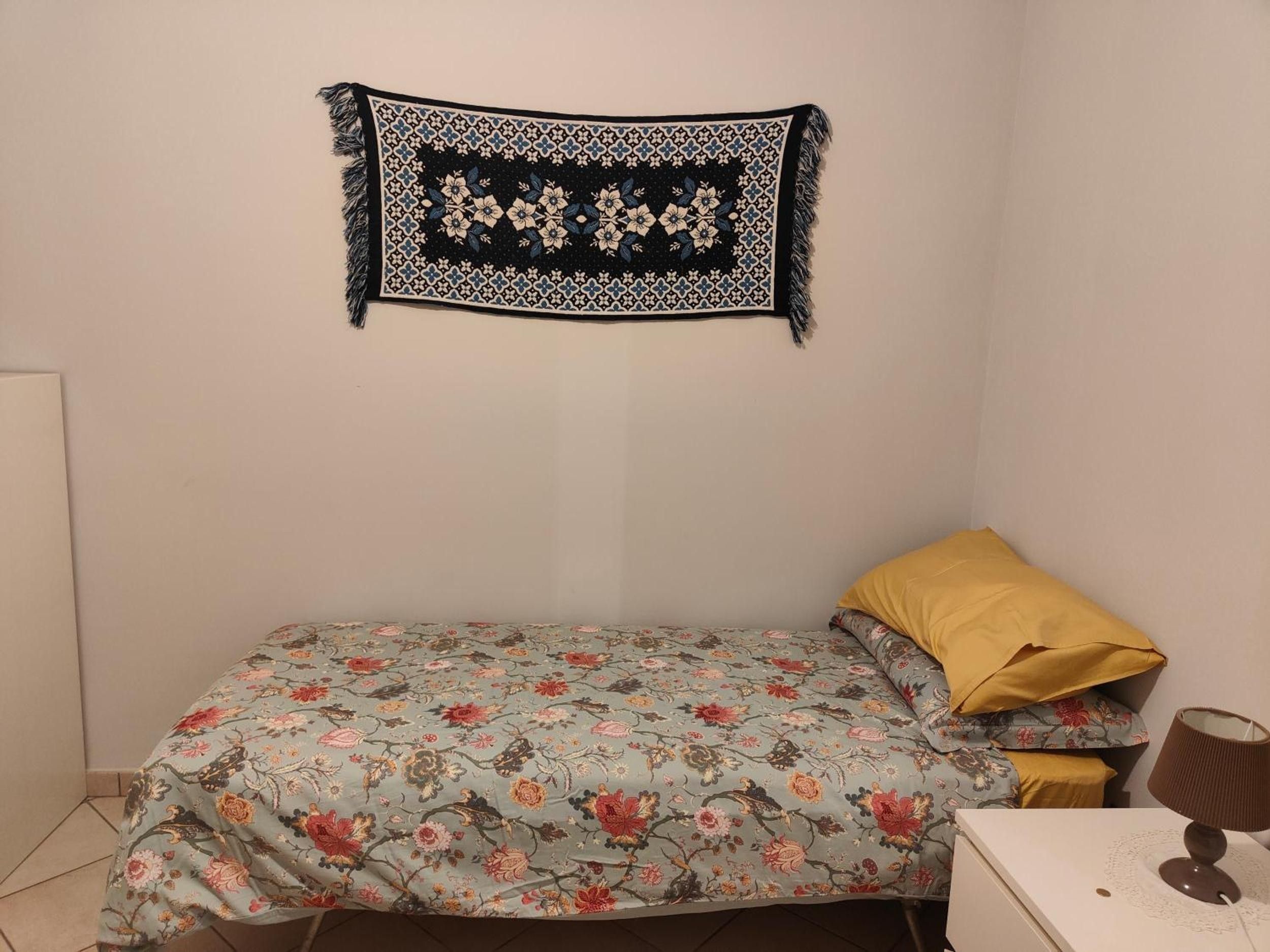 Ein Schlafzimmer mit einem Bett, einem Nachttisch, einer Lampe und einer Wanddekoration.