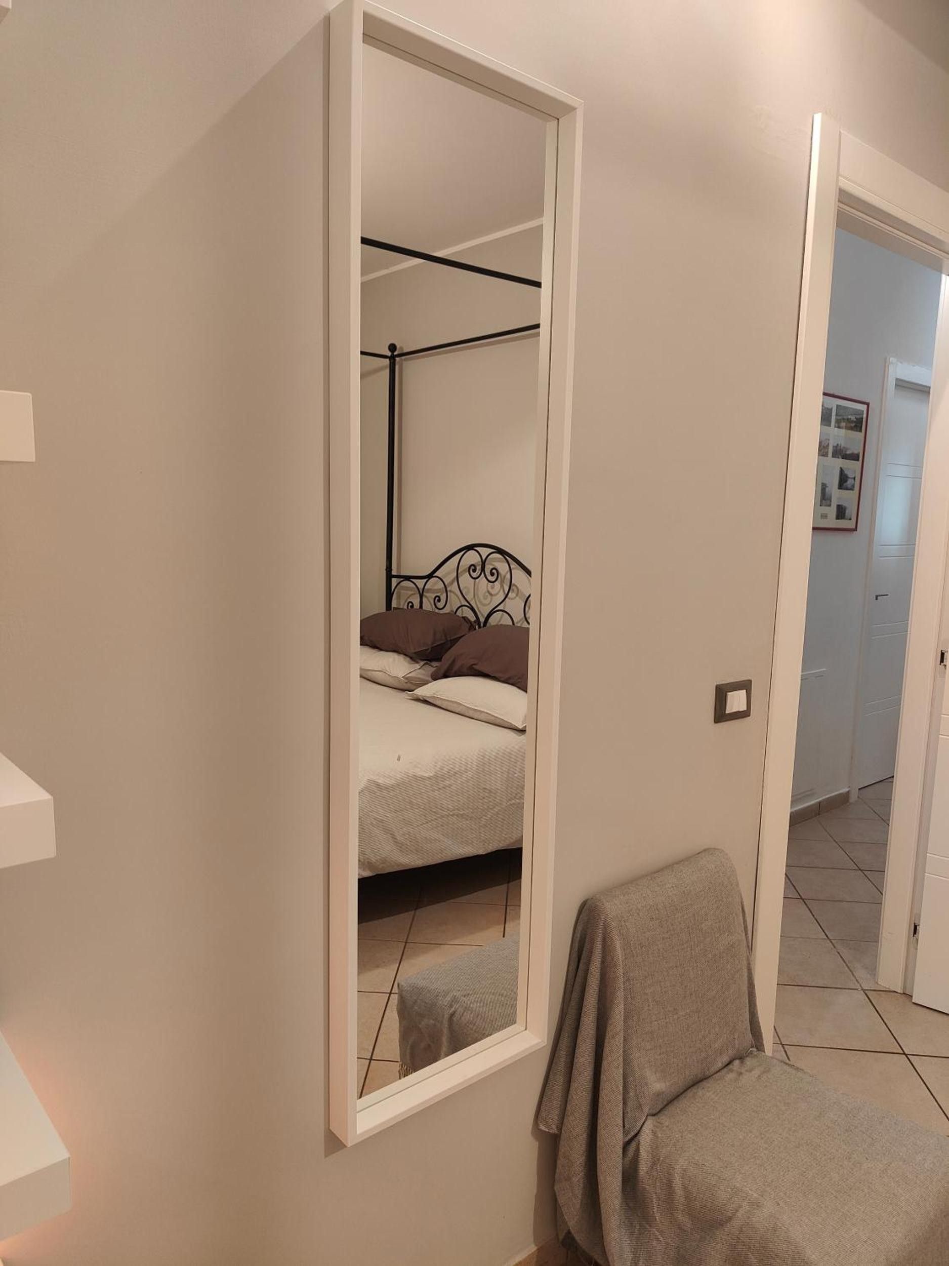 Ein Schlafzimmer mit einem Bett, einem Sessel und einem großen Spiegel.