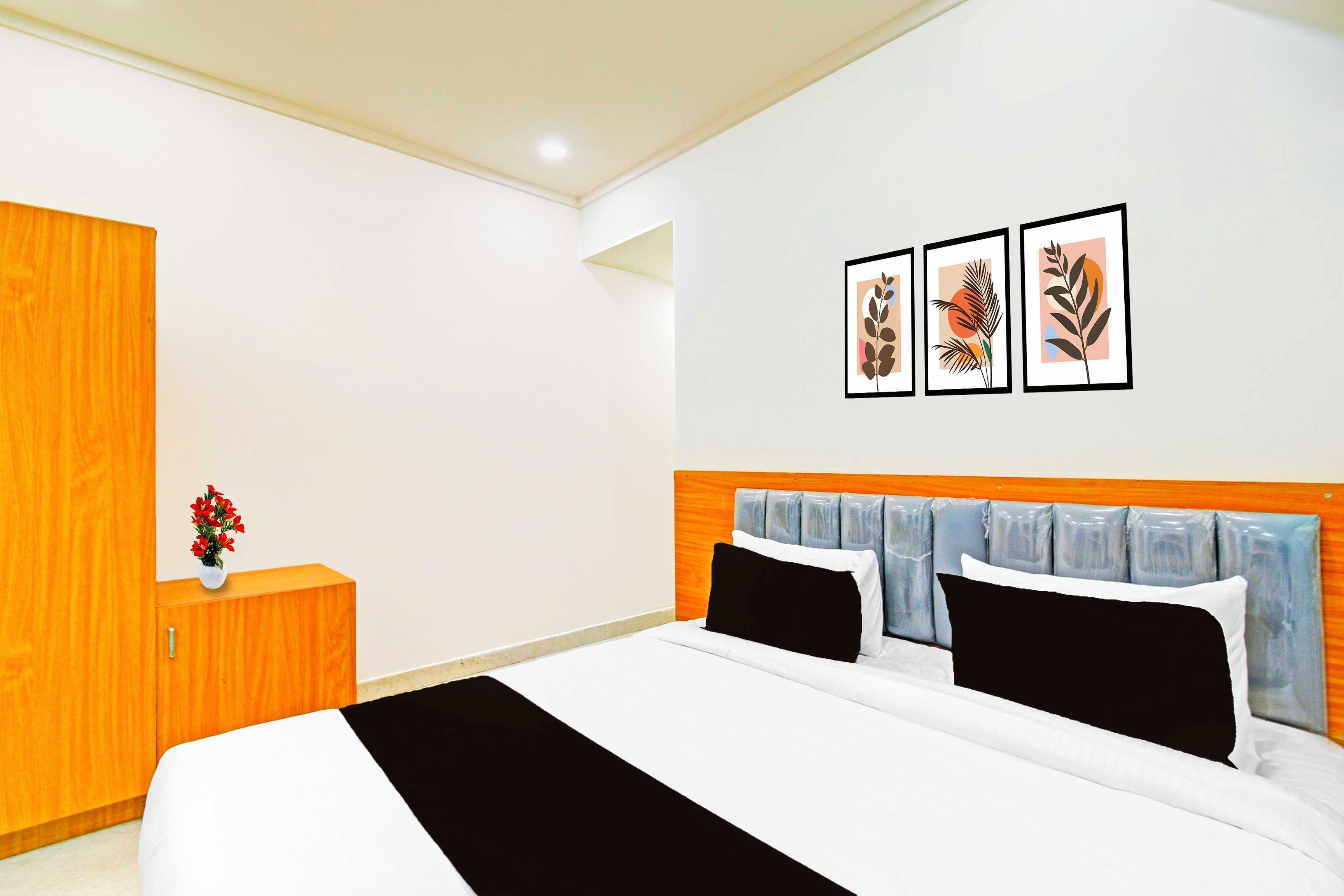 Un dormitorio con una cama, un armario de madera y una mesita de noche con un florero.