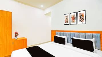 Un dormitorio con una cama, un armario de madera y una mesita de noche con un florero.
