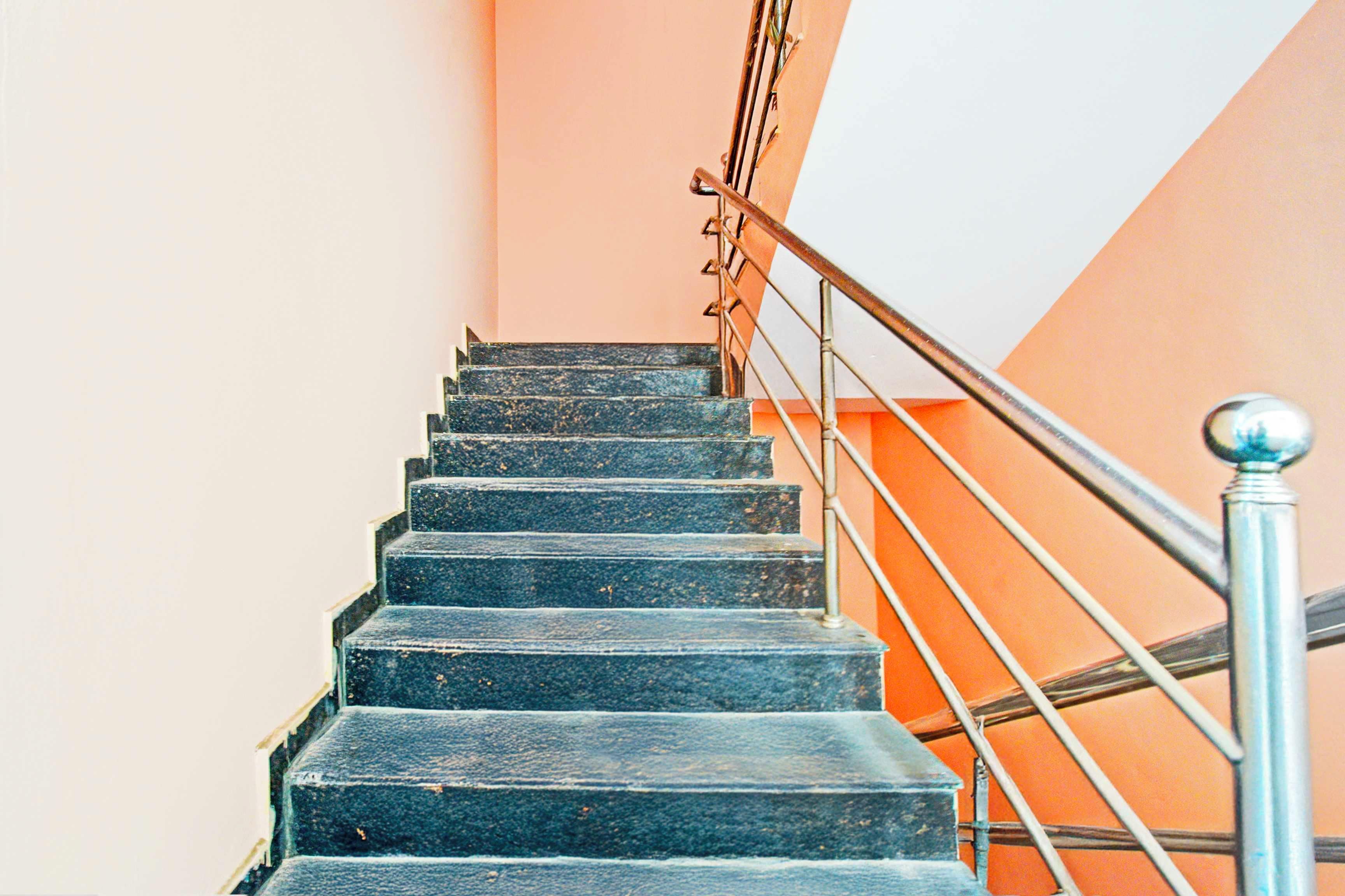 A staircase with metal railings and a handrail, leading upwards.