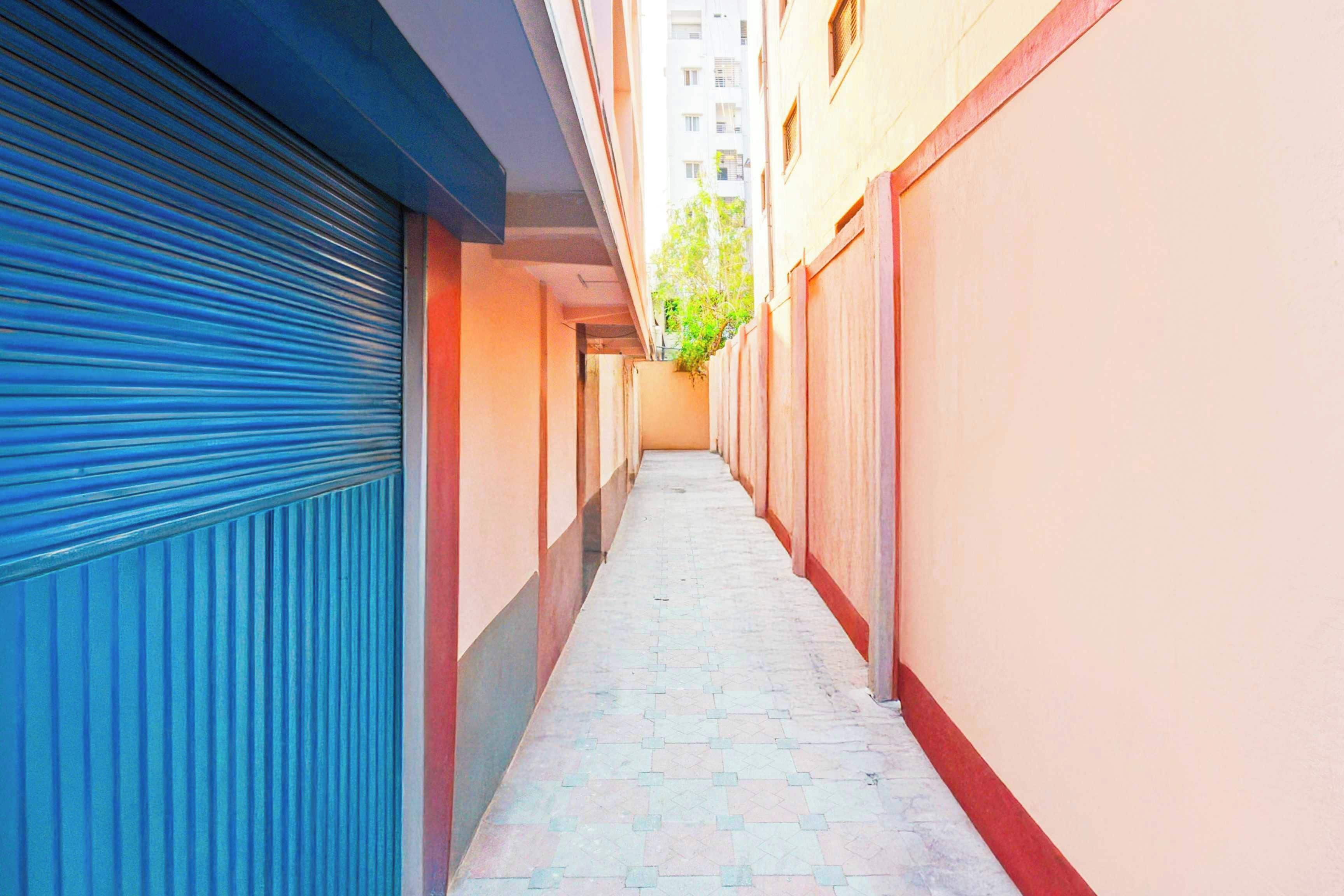 Un pasillo estrecho con contraventanas cerradas a la izquierda y un piso de baldosas.