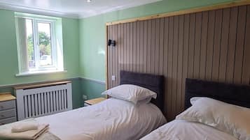 A room with two beds, a window, and a radiator.