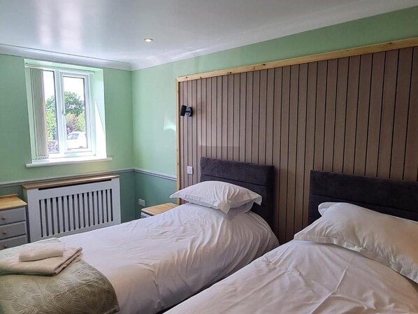A room with two beds, a window, and a radiator.