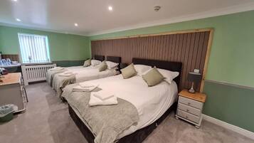 Habitación de hotel con dos camas, una mesita de noche, una lámpara y un ventanal con persianas.