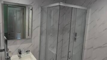 A bathroom with a glass-enclosed shower, a white sink, and a toilet.
