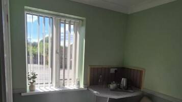 A room with a bed, a desk, a chair, a radiator, and a window.