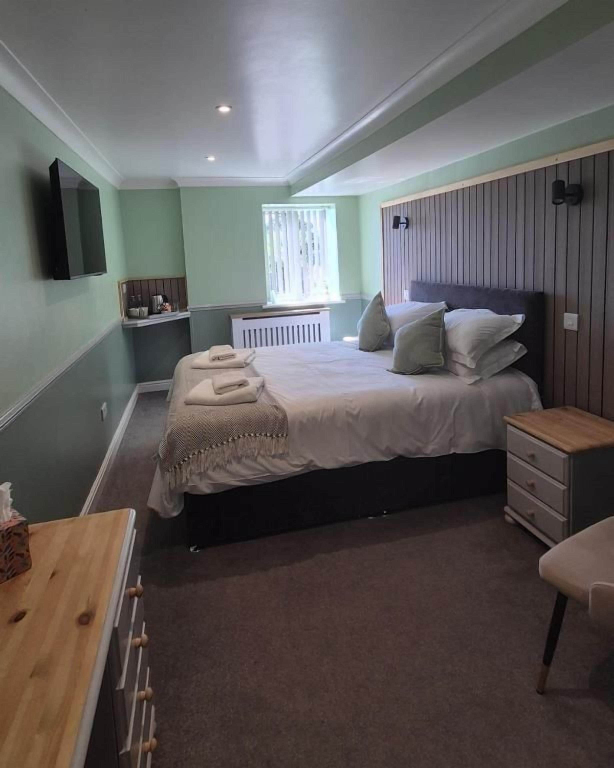 Quarto com cama, mesa de cabeceira e janela.