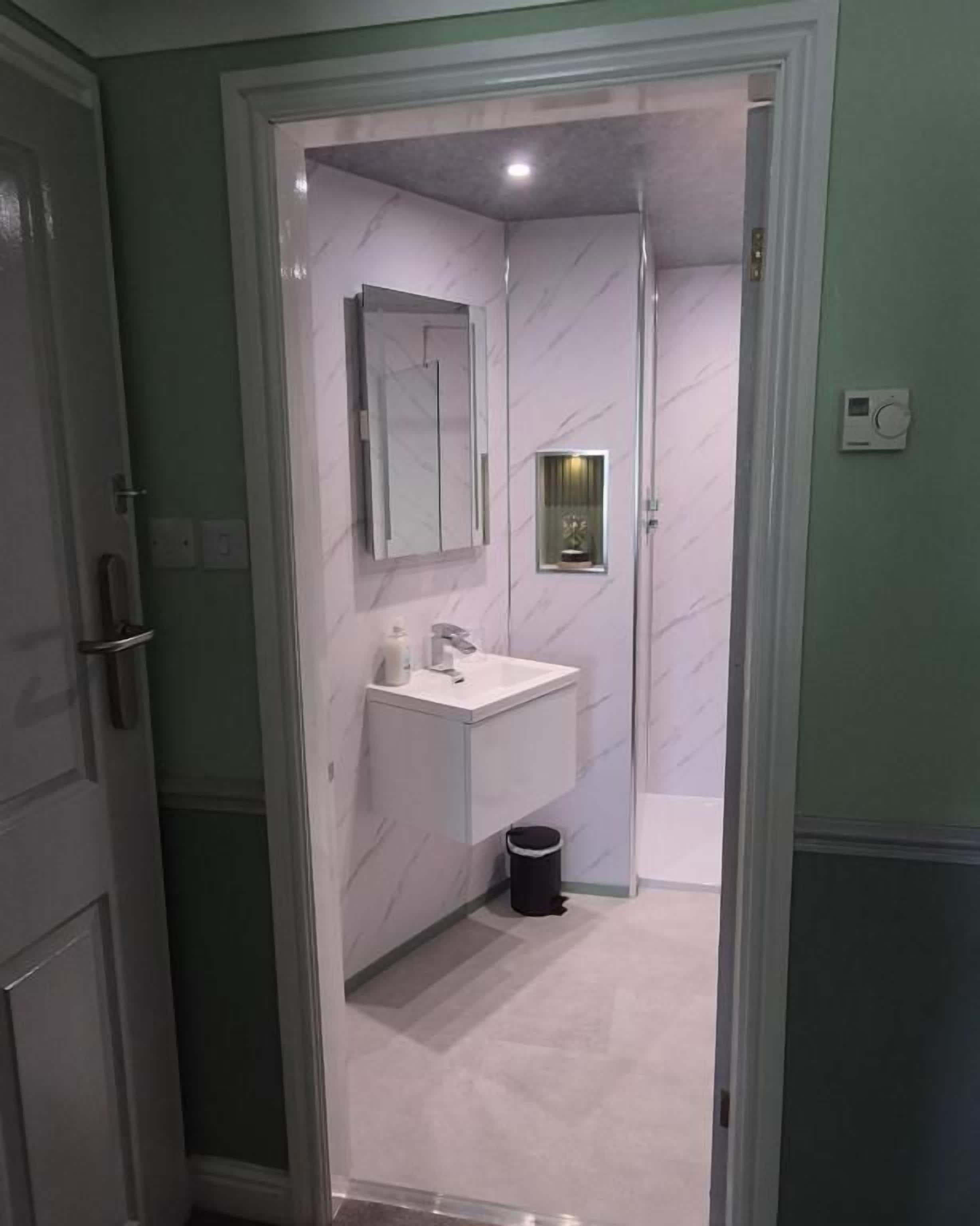 Un bany amb un lavabo blanc, un mirall i un gresol.