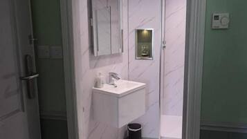 Ein Badezimmer mit einem weißen Waschbecken, einem Spiegel und einem Mülleimer.
