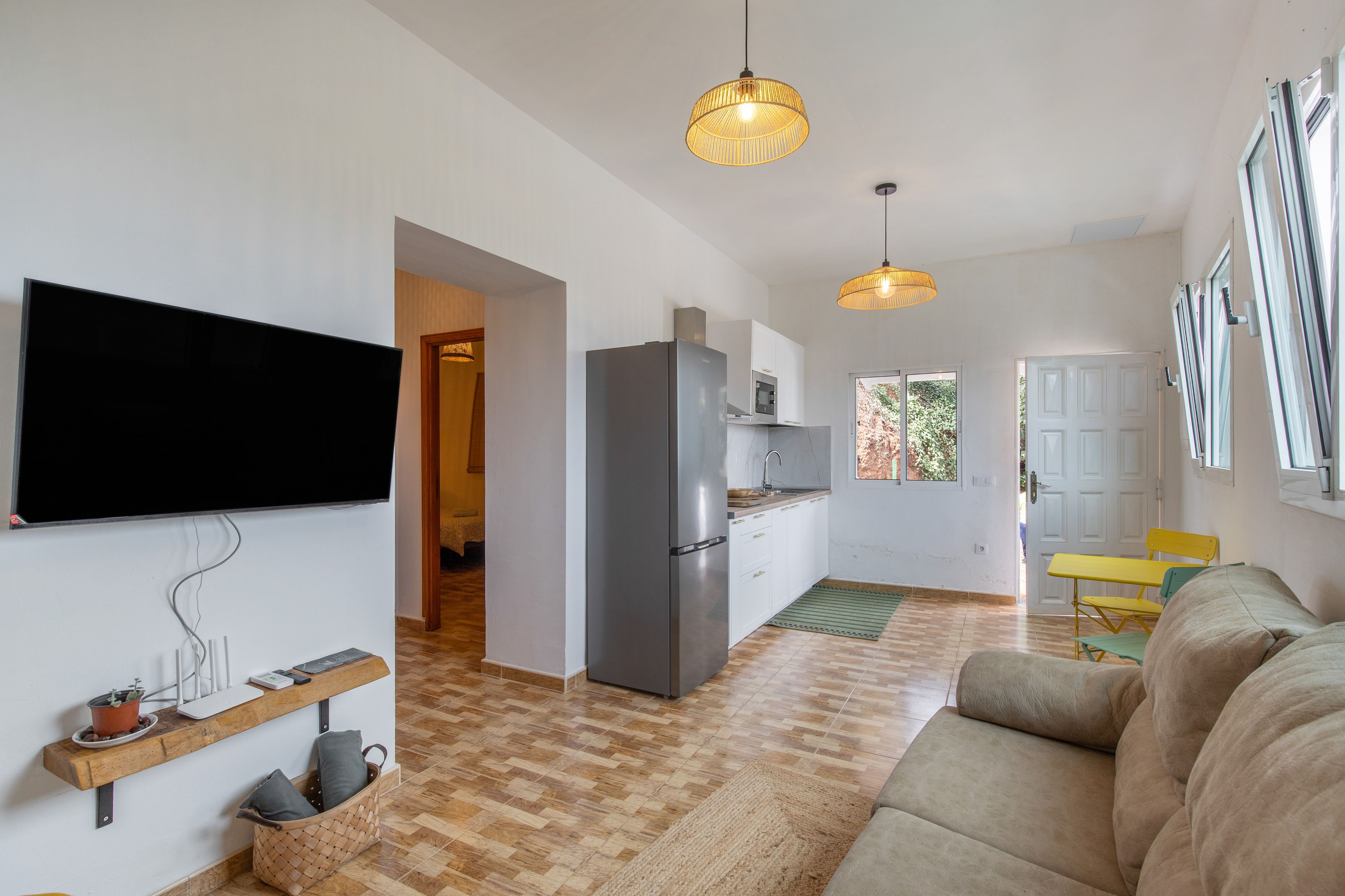 Eine moderne Küche mit Kühlschrank, Flachbildfernseher und Pendelleuchten.