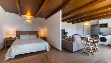 Un dormitorio con una cama grande y lámparas de noche, un sofá y un comedor con mesa y sillas.