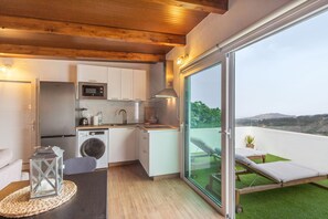 A compact kitchen with modern appliances, a washing machine, and a balcony with a view.