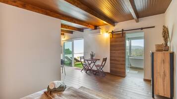 Une chambre moderne avec un grand lit, un plafond en bois, une vue sur l’extérieur et une petite table avec des chaises.