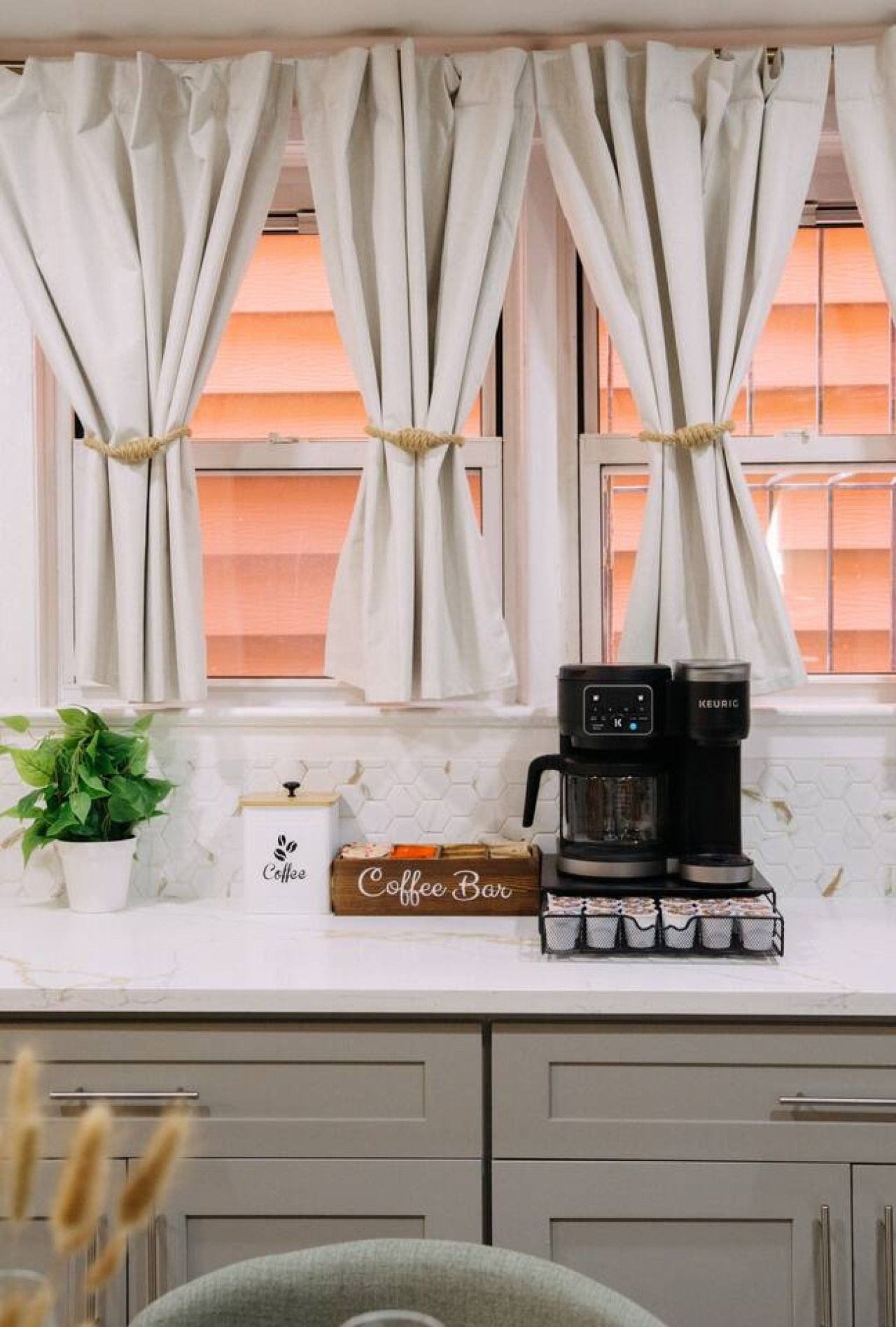 A kitchen with a coffee maker, a coffee box, and a potted plant.