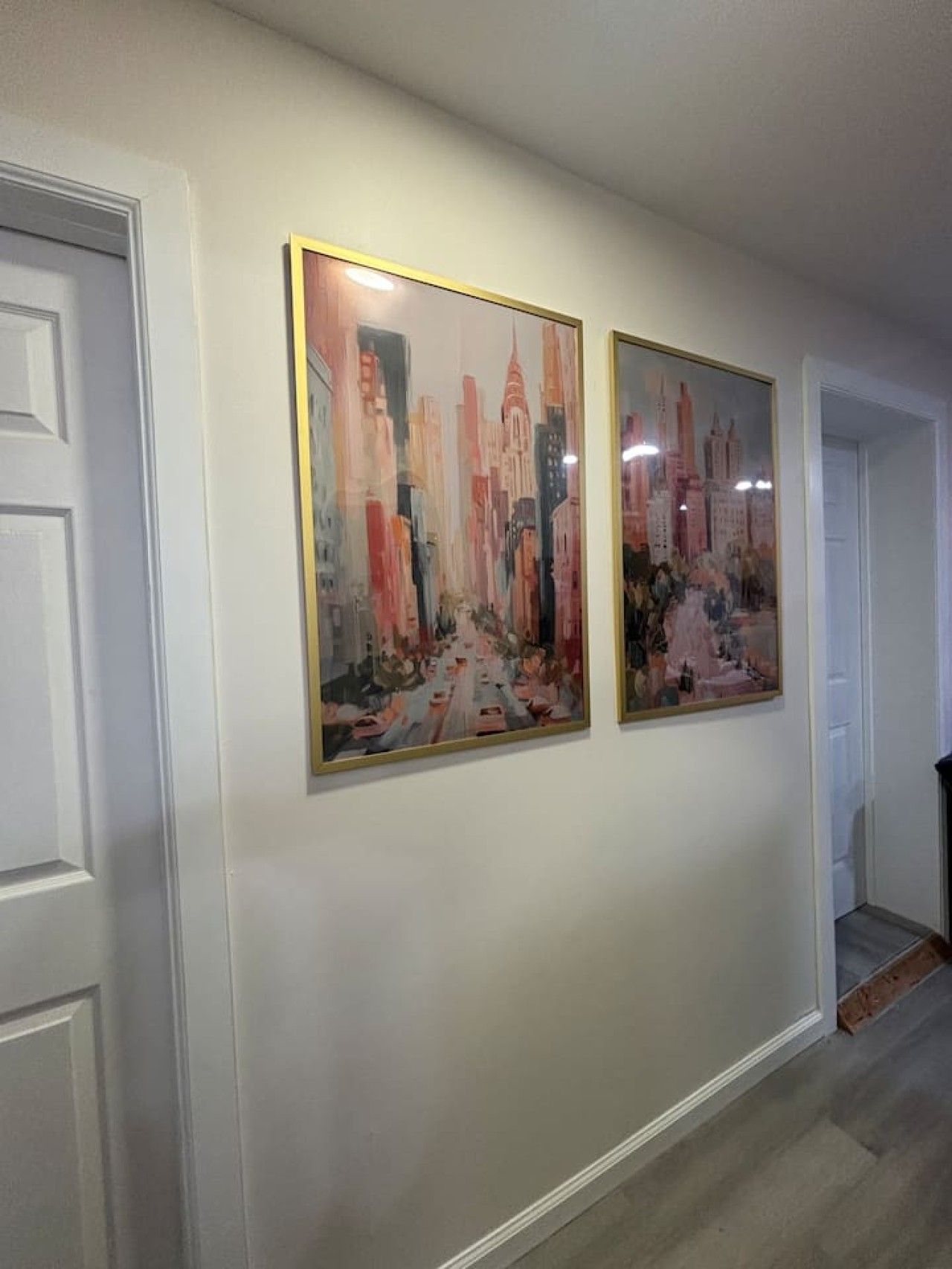A hallway with two framed paintings on the wall.