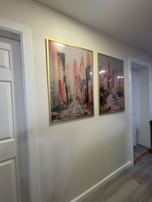 A hallway with two framed paintings on the wall. - NEW Chic Retreat min NYC & MetLife Private Parking (North Bergen)