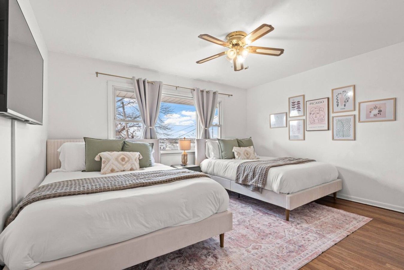 A bedroom with two beds, a ceiling fan, and a window with curtains.