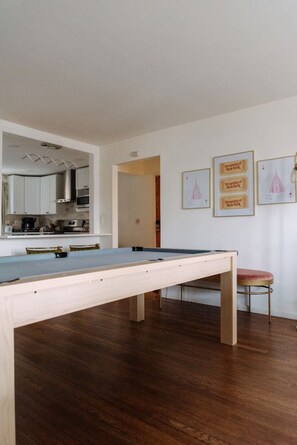 A room with a pool table, wooden flooring, a kitchen area, and framed pictures on the wall. - Big City Haven w/Parking 4 Cars & Private Backyard (North Bergen)