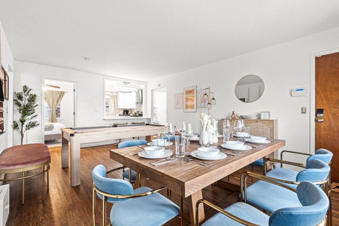 A modern dining area with a wooden table set for six, surrounded by blue upholstered chairs.
