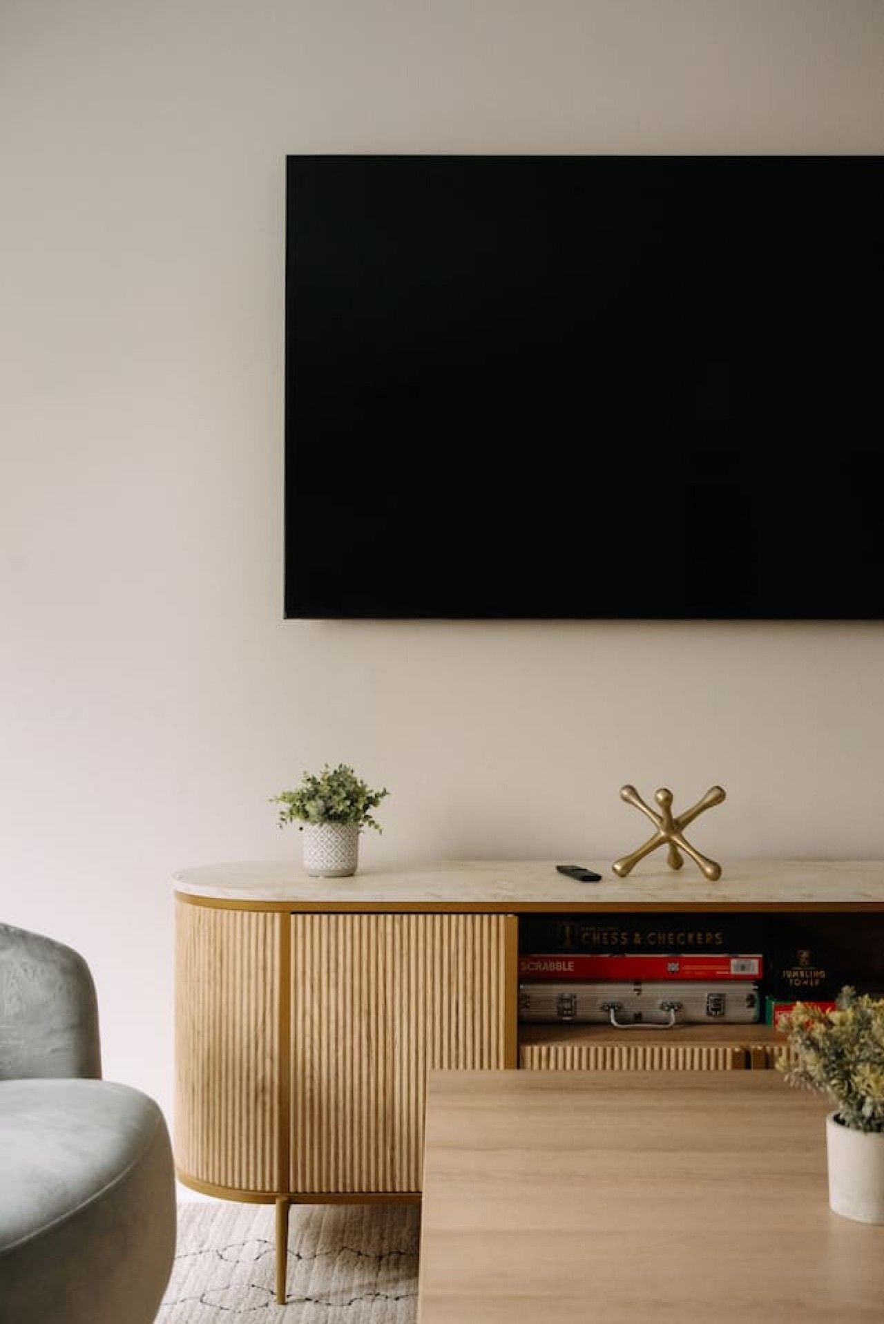 Una sala moderna con un mueble de madera, un televisor de pantalla plana en la pared y una pequeña mesa con una planta en maceta.