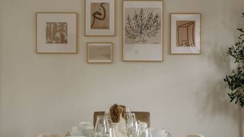 Una mesa de comedor dispuesta con platos y vasos blancos, rodeada de sillas color beige.