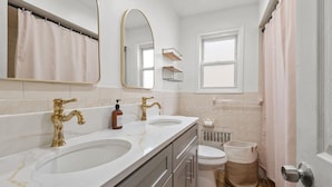 A bathroom with two sinks, a toilet, a shower curtain, a mirror, and a window. - Big City Retreat with Parking (North Bergen)
