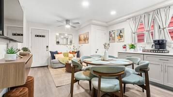 A modern kitchen with a dining area, a ceiling fan, and a coffee machine.