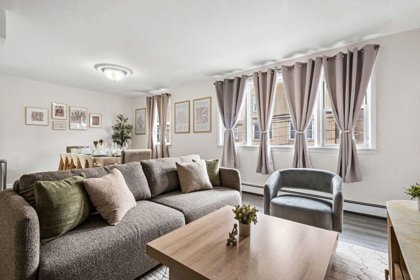 Una sala de estar moderna con un sofá, una silla, una mesita de centro y un comedor con una mesa dispuesta para dos personas.
