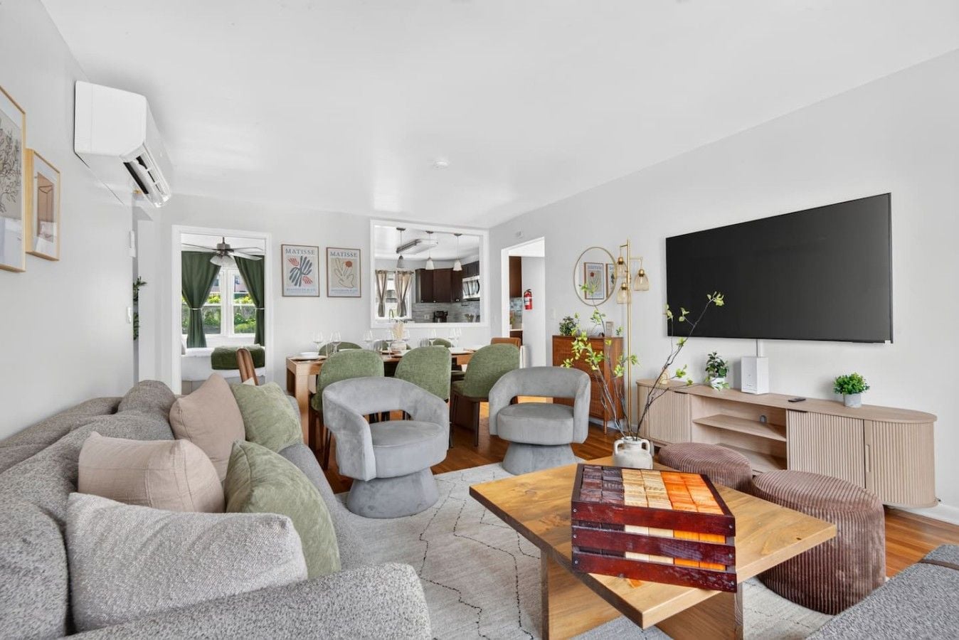 A modern living room with a sofa, chairs, a coffee table, and a flat-screen TV.